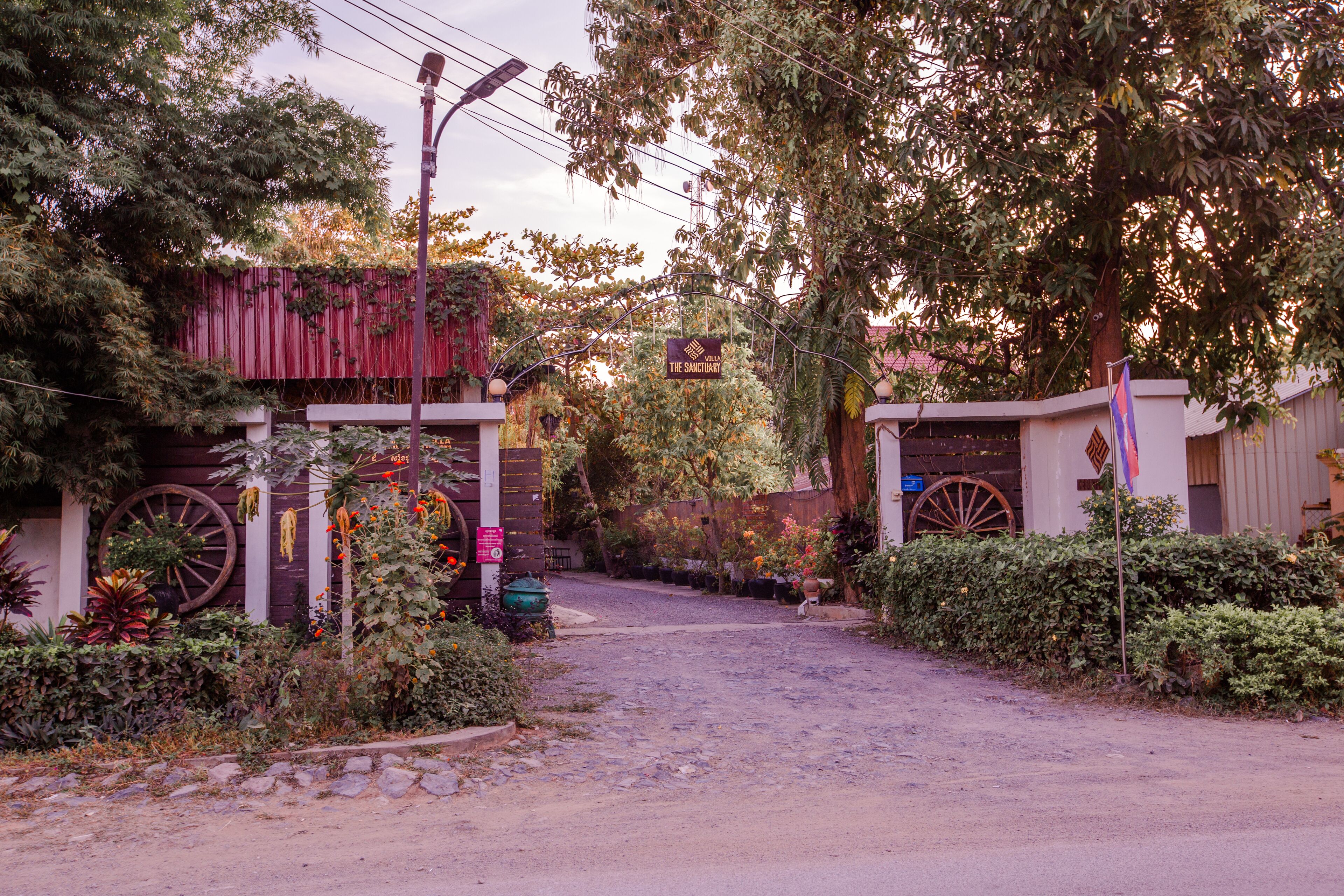 A rustic entrance with a wooden fence, a large wheel, and a sign indicating a sanctuary.