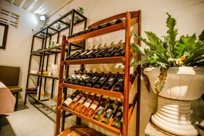 A wine rack with multiple bottles, a potted plant, and a mirror on the wall.