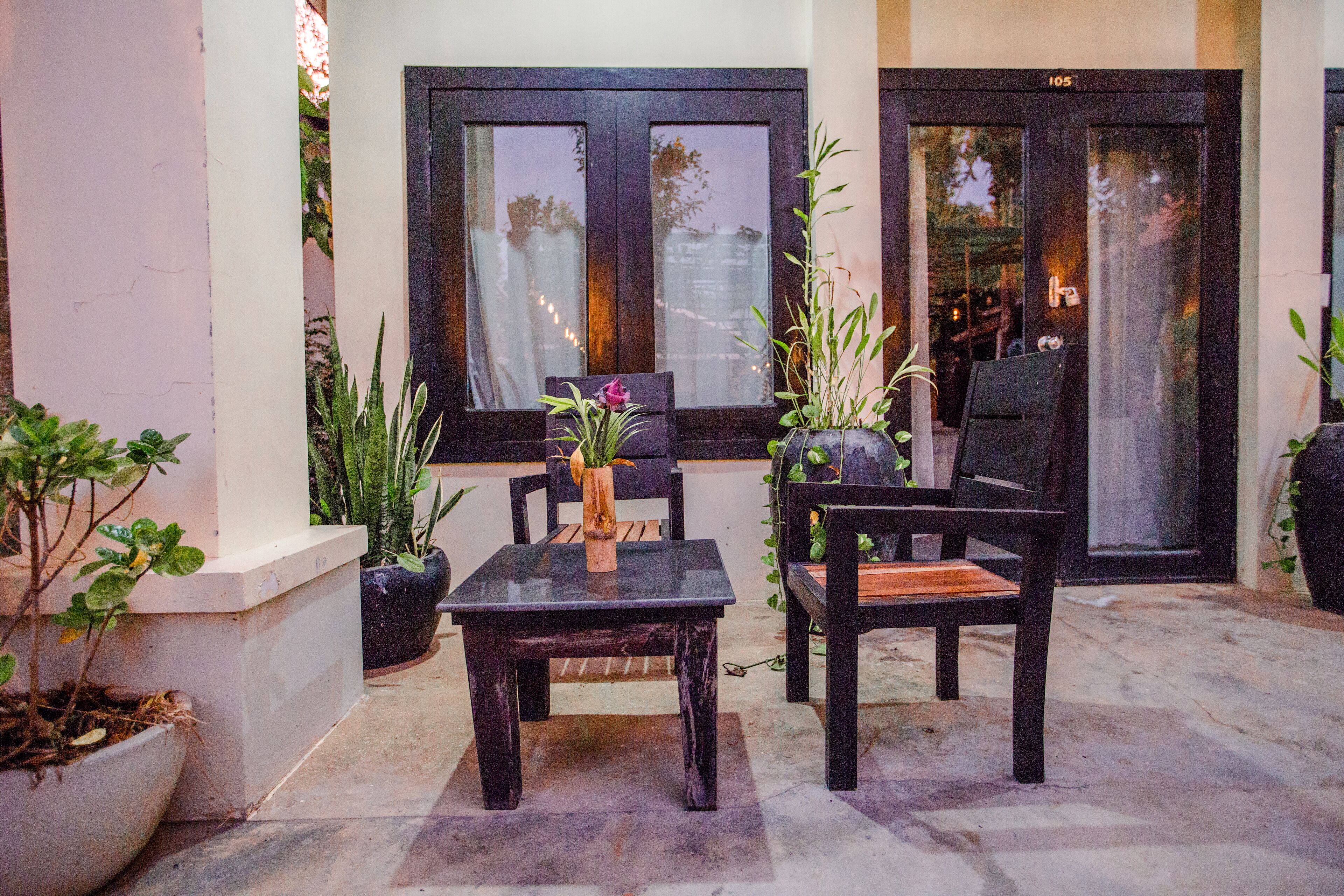 Un espace extérieur aménagé avec une table et des chaises, entouré de plantes en pot.