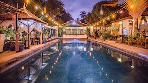 A serene pool area with a clear view of the pool, surrounded by potted plants and string lights. - The Sanctuary Villa Battambang (Battambang)