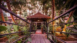 A wooden bridge leading to a gazebo surrounded by tropical plants and trees. - The Sanctuary Villa Battambang (Battambang)