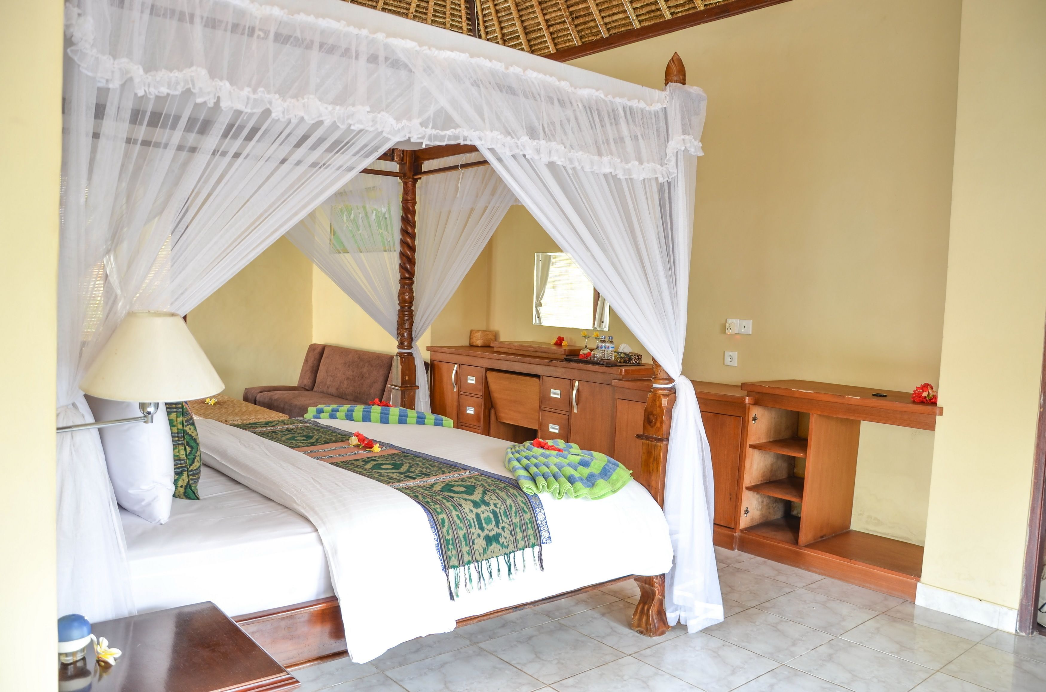 A room with a four-poster bed, a wooden nightstand, a bedside table, and a wooden cabinet with shelves.