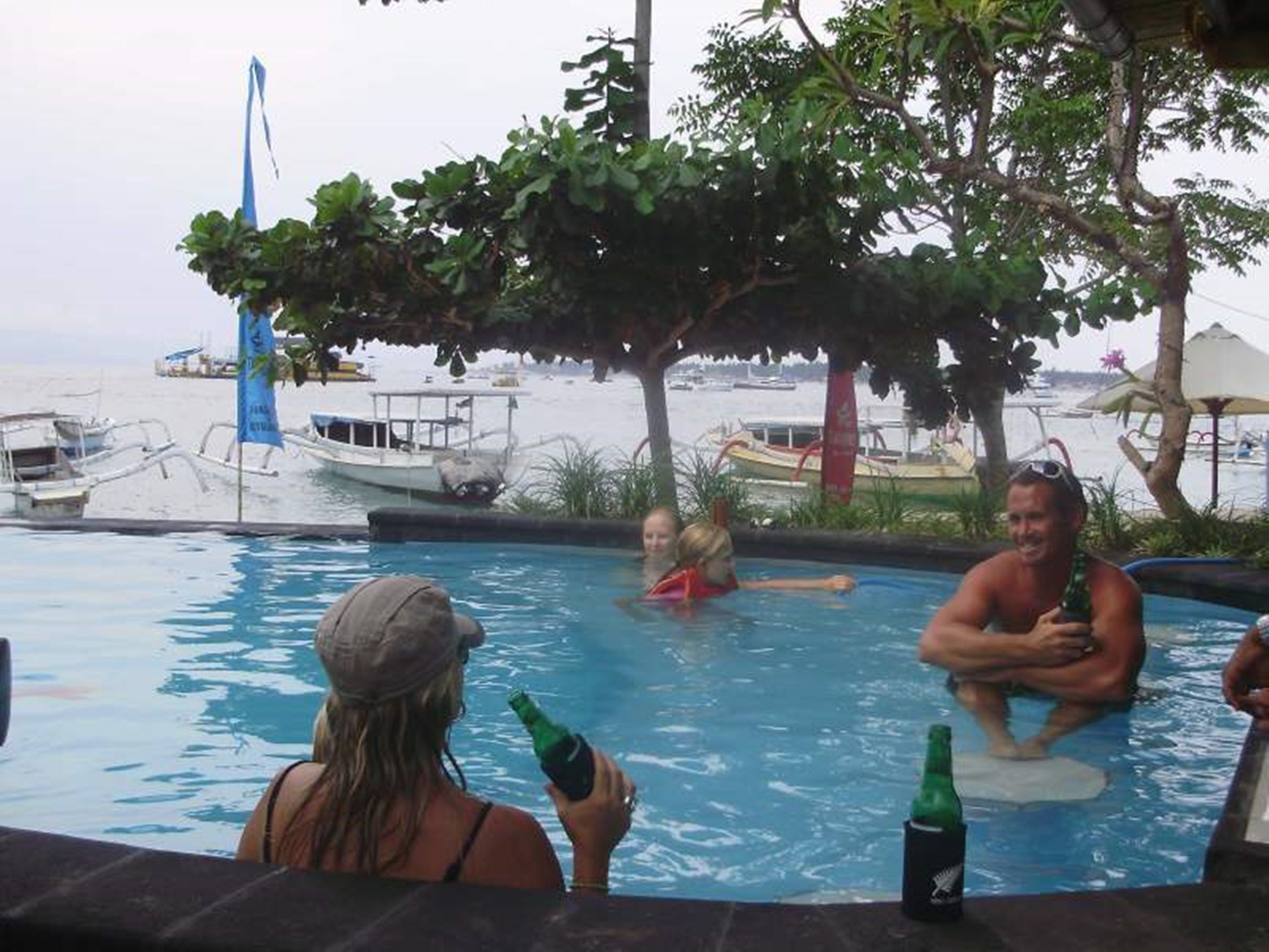 A pool area with boats and a beach in the background.