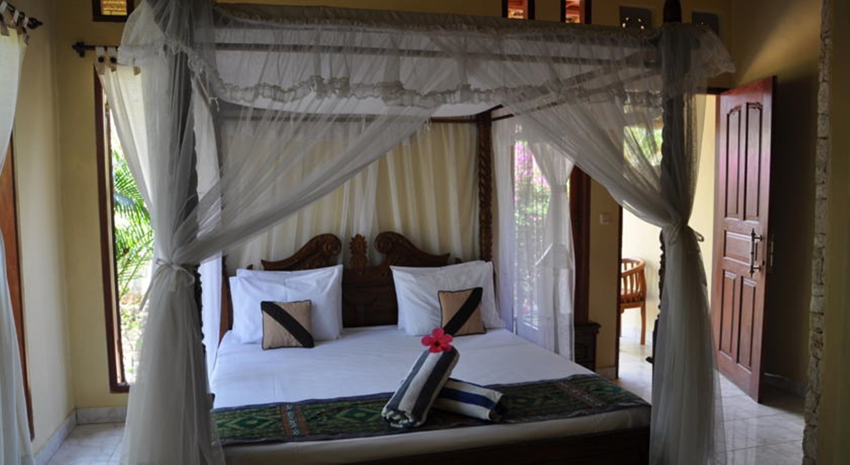 A bed with a canopy, pillows, and a book.