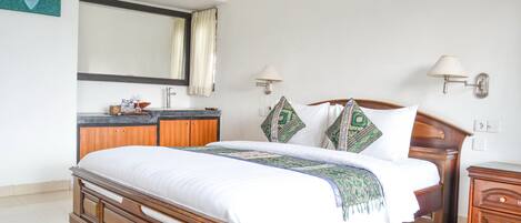 A bedroom with a wooden bed, a nightstand, a dresser, a mirror, and two wall-mounted lamps.