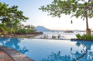 Une piscine à débordement offrant une vue sur les bateaux et, au loin, sur une montagne.