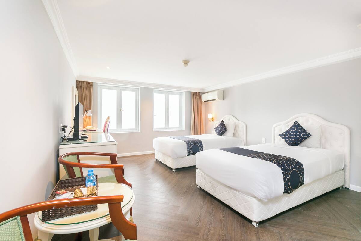 Ein Hotelzimmer mit zwei Betten, einem Schreibtisch, einem Stuhl und einem Fenster.