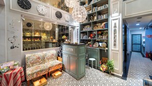 A reception area with a green counter, a patterned sofa, and a bookshelf filled with books. - Sabina Residence - Stellar Boutique Hotel (Ho Chi Minh City)