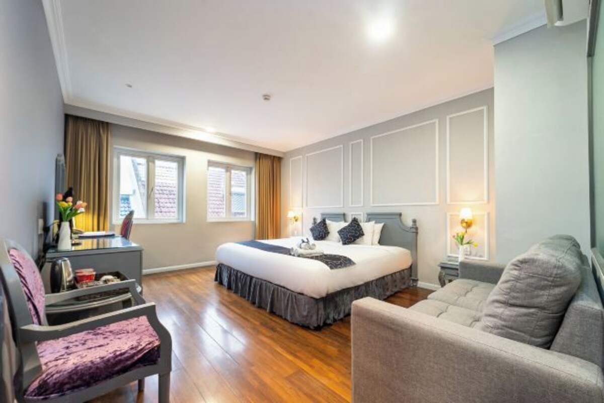 Una habitación de hotel con una cama grande, un escritorio, una silla y un sofá.