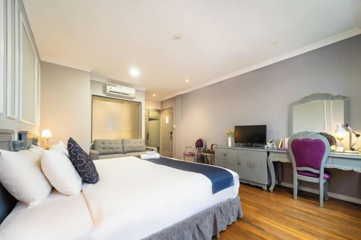 Ein Hotelzimmer mit Bett, Schreibtisch, Stuhl, Fernseher und Spiegel.