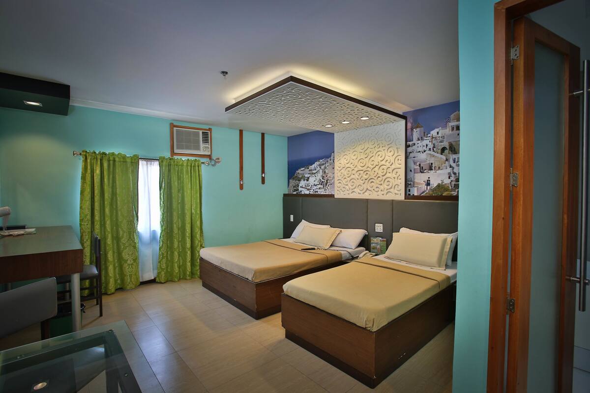 A hotel room with two beds, a desk, and a chair.