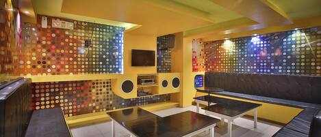A modern living room with a sofa, two tables, a TV, and a wall with circular patterns.