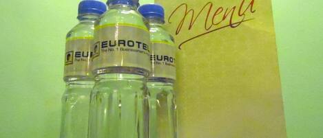 Four bottles of water labeled "EUROTEL" and a brown paper bag with the word "Menu" written on it.