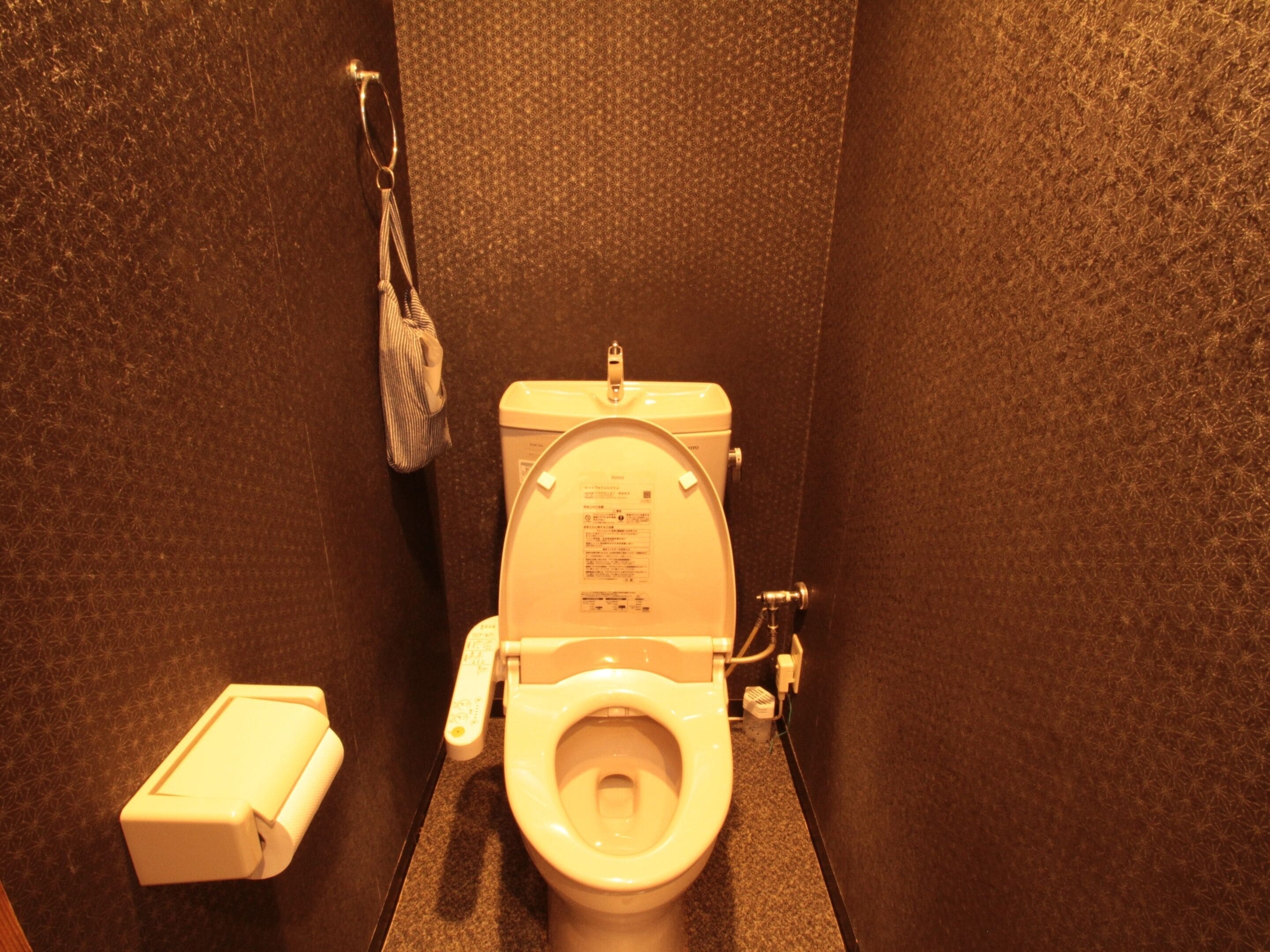 Een kleine, praktische badkamer met toilet, handdroger en prullenbak.