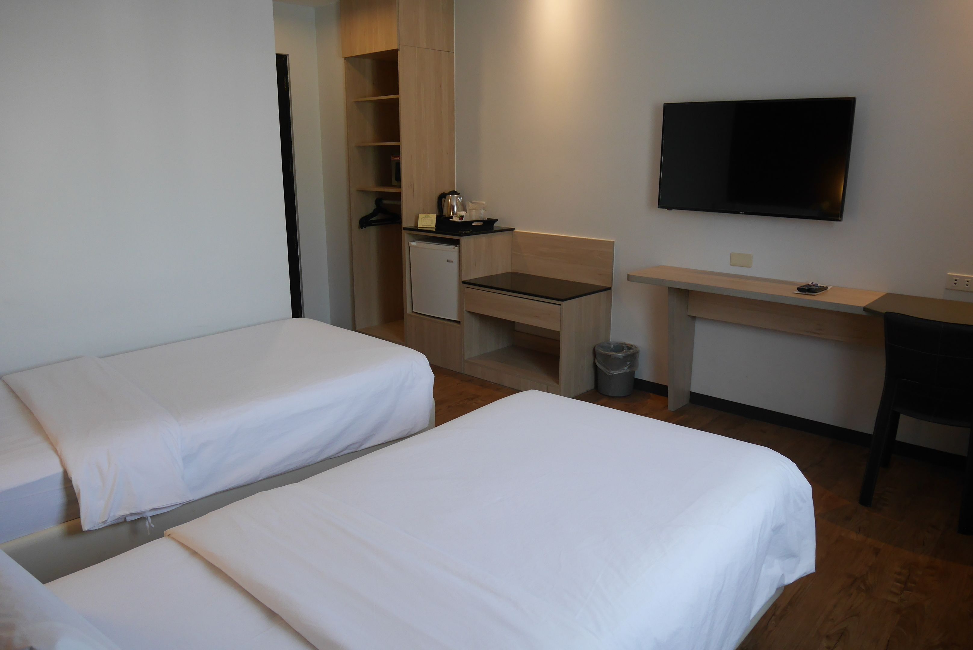 Une chambre d’hôtel avec deux lits simples, un bureau, une télévision et une petite kitchenette.