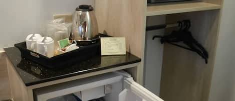 Un angolo cottura compatto con frigorifero, forno a microonde e macchina del caffè.