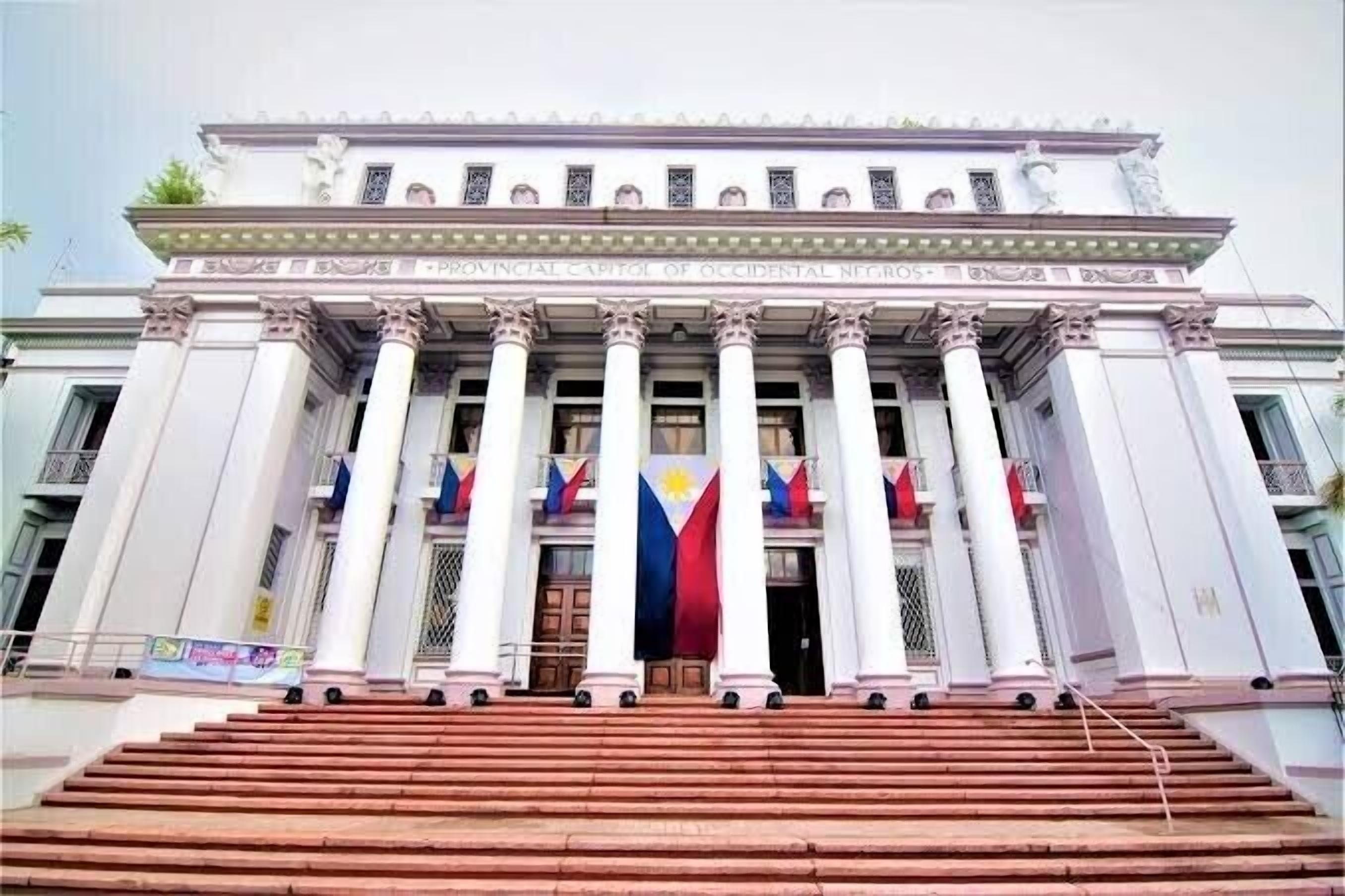 A grand building with a central entrance flanked by columns, featuring a prominent flag display.