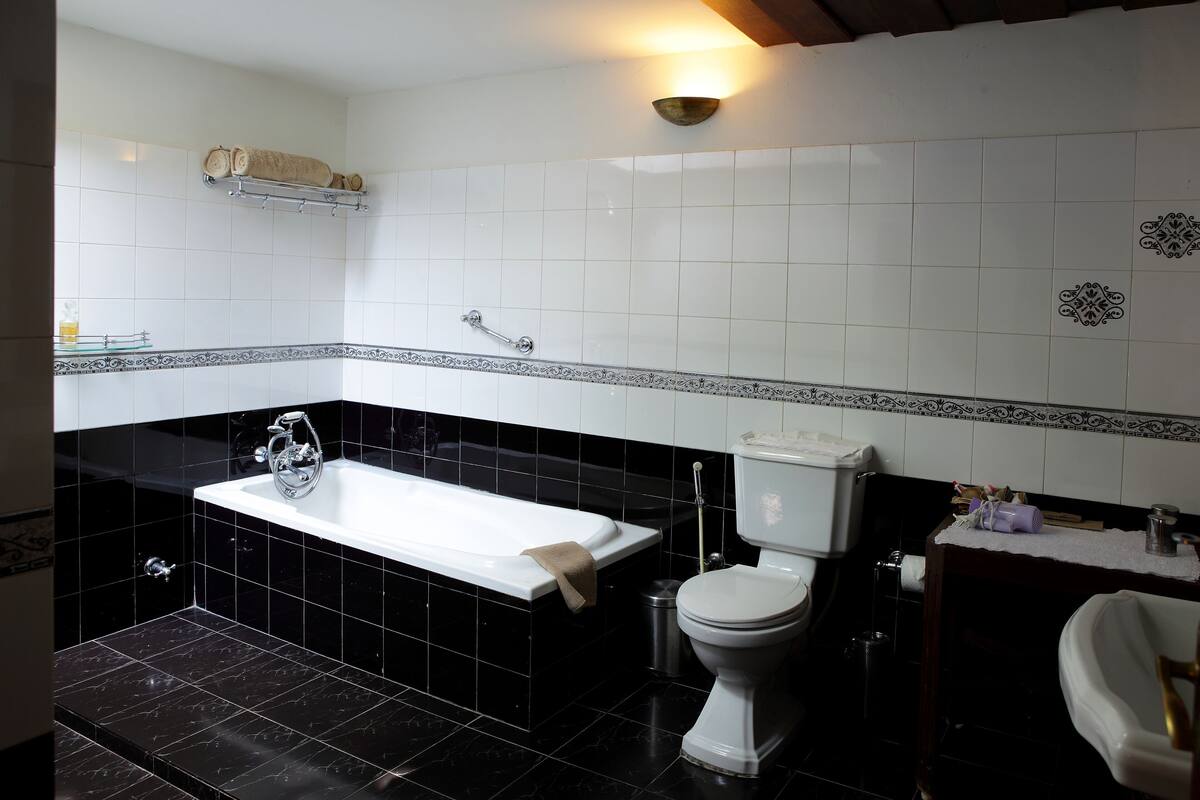 A bathroom with a bathtub, toilet, sink, and a shelf with towels.