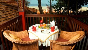 Comedor con sillas de mimbre y una mesa dispuesta para dos, con vista a la playa.