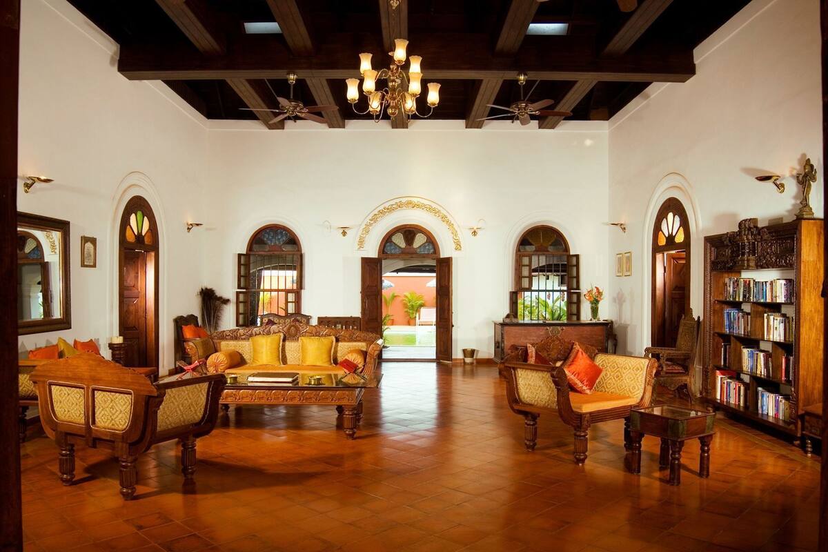 A spacious room with a high ceiling, wooden furniture, and a chandelier.