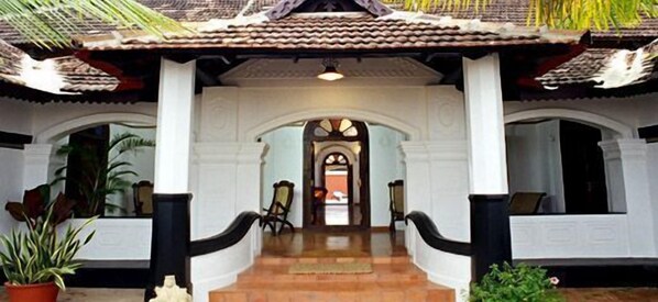 A traditional building with a tiled roof, white walls, and a central staircase leading to an entrance.