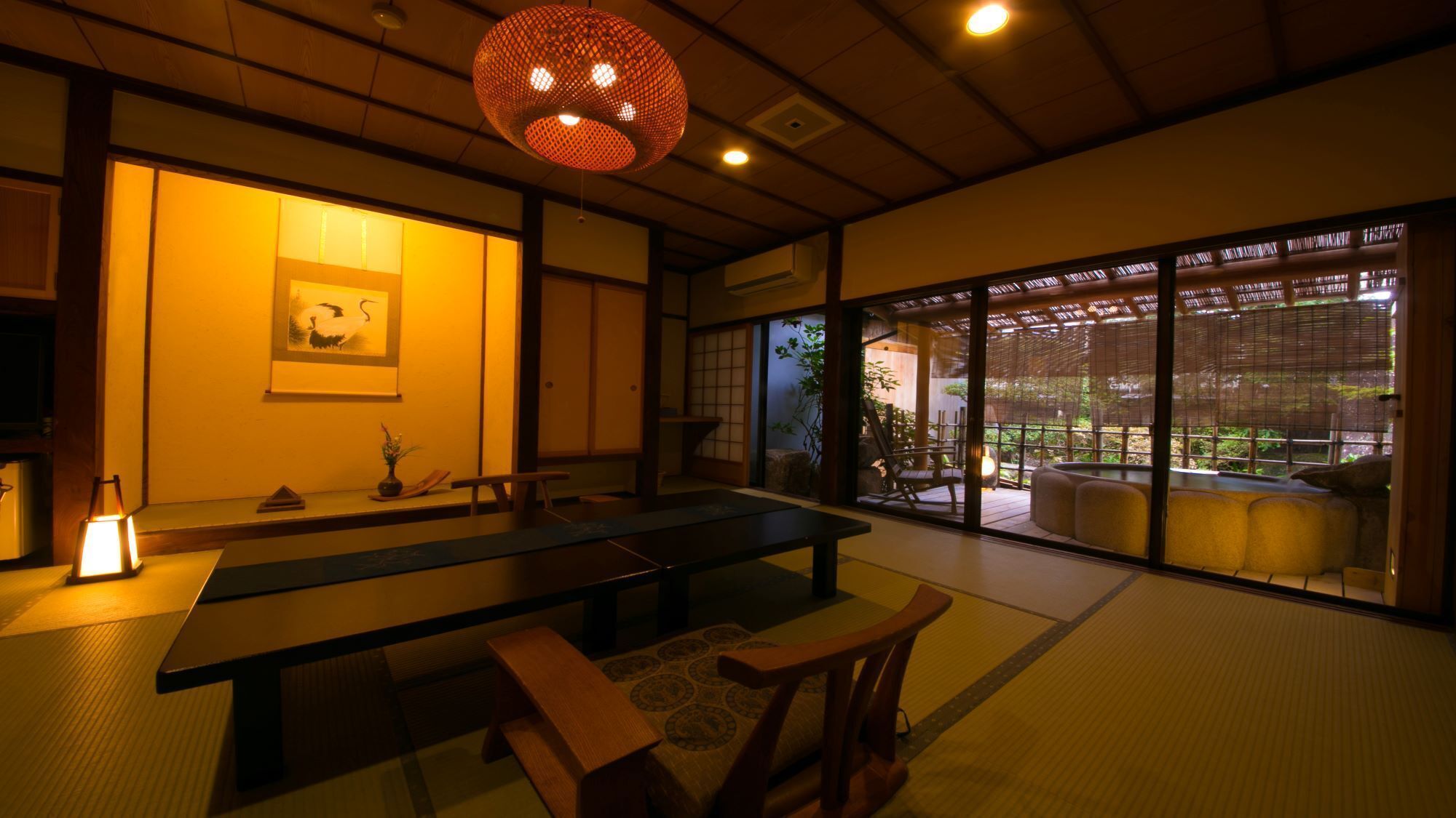 Ein traditioneller japanischer Raum mit Tatami-Bodenbelag, einem niedrigen Tisch und Schiebetüren, die zu einem Garten führen.