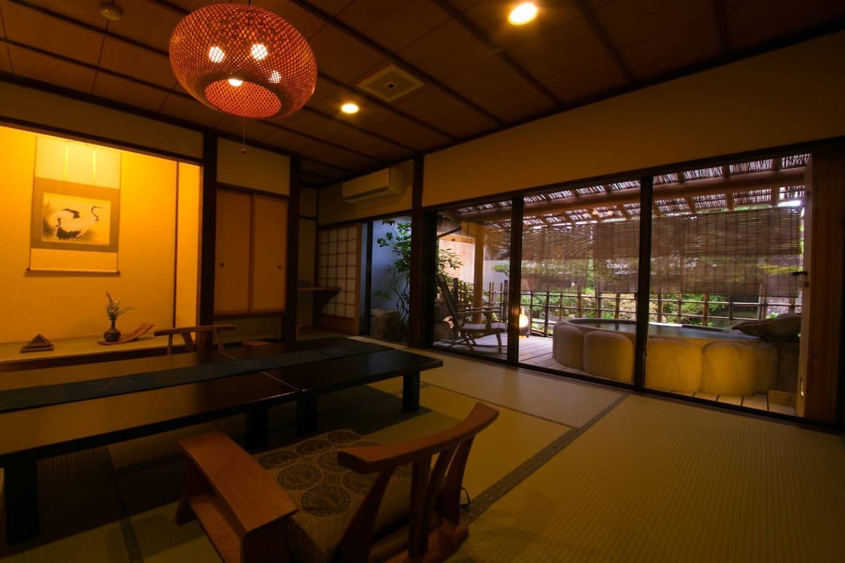 A traditional Japanese room with tatami flooring, a low table, and sliding doors leading to a garden.