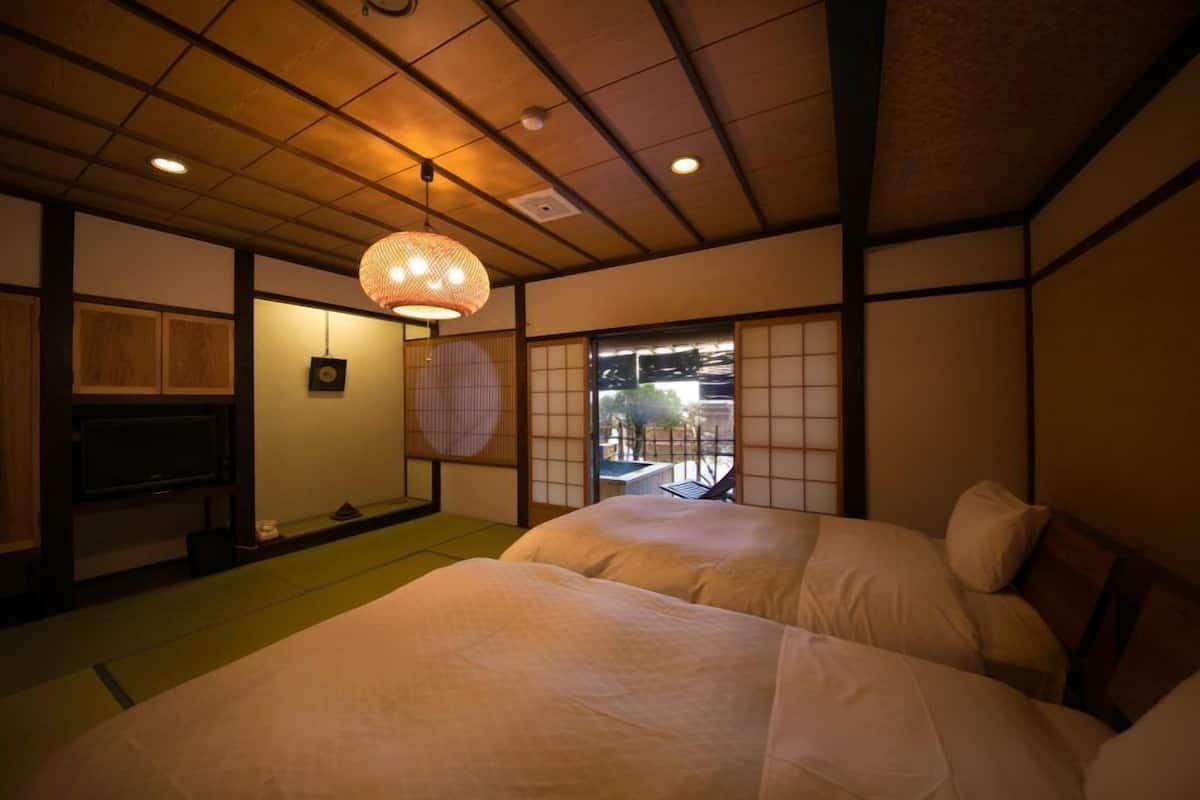 A traditional Japanese-style room with tatami flooring, a low wooden ceiling, and a large window with a view of the outside.