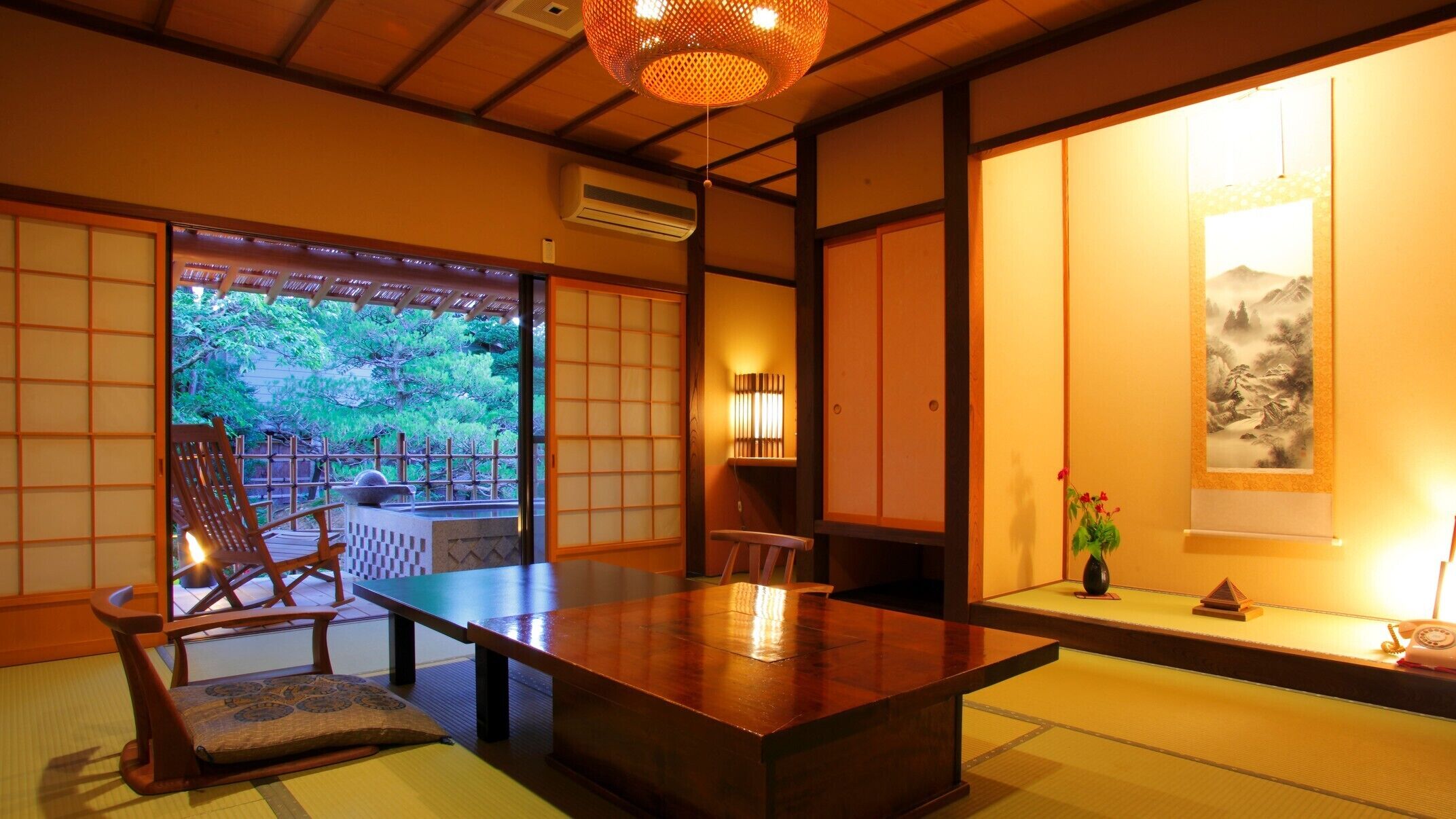 Ein traditioneller japanischer Raum mit Tatami-Bodenbelag, einem niedrigen Tisch und Blick auf einen Garten.