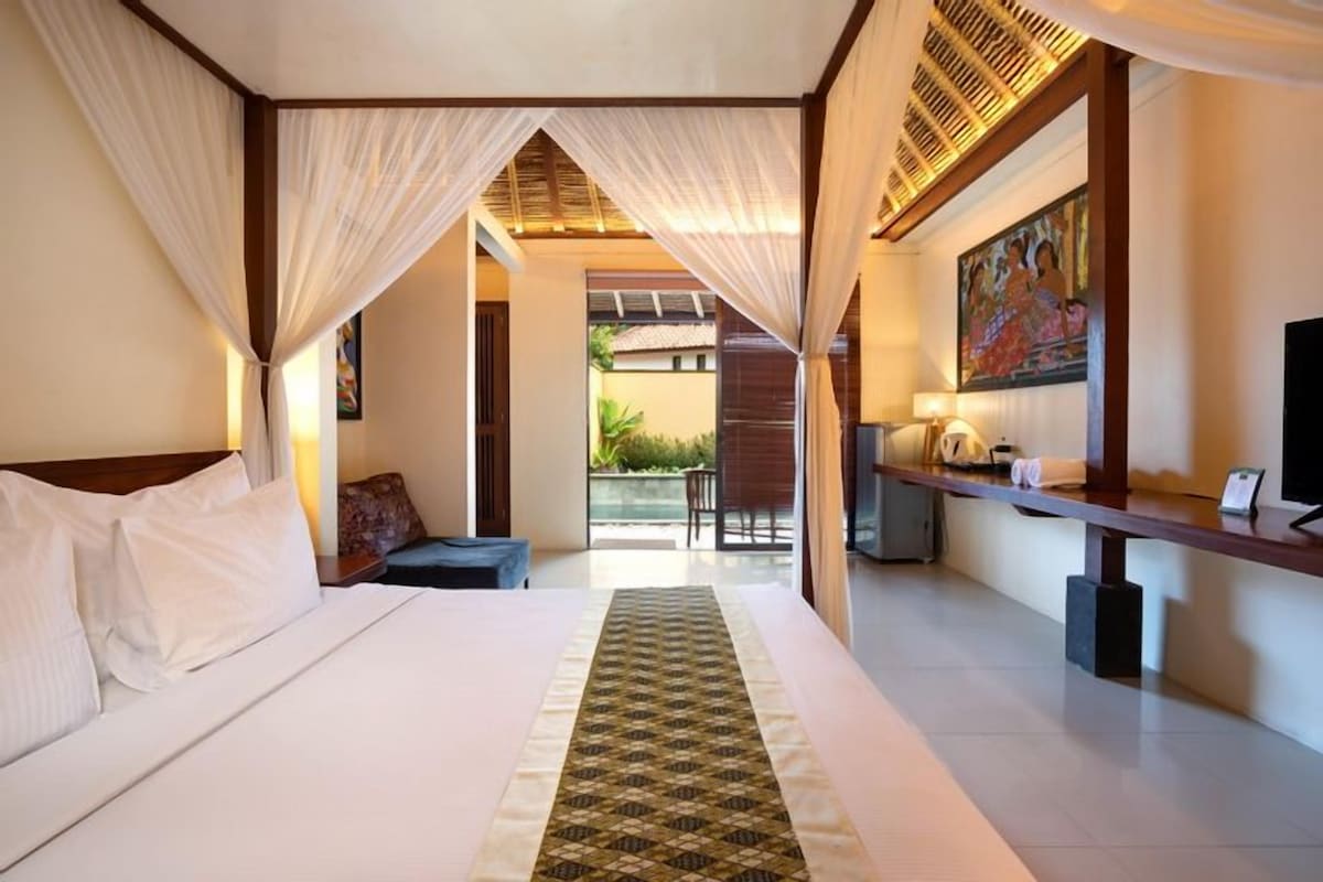 A hotel room with a bed, a desk, a chair, and a view of the outdoors.