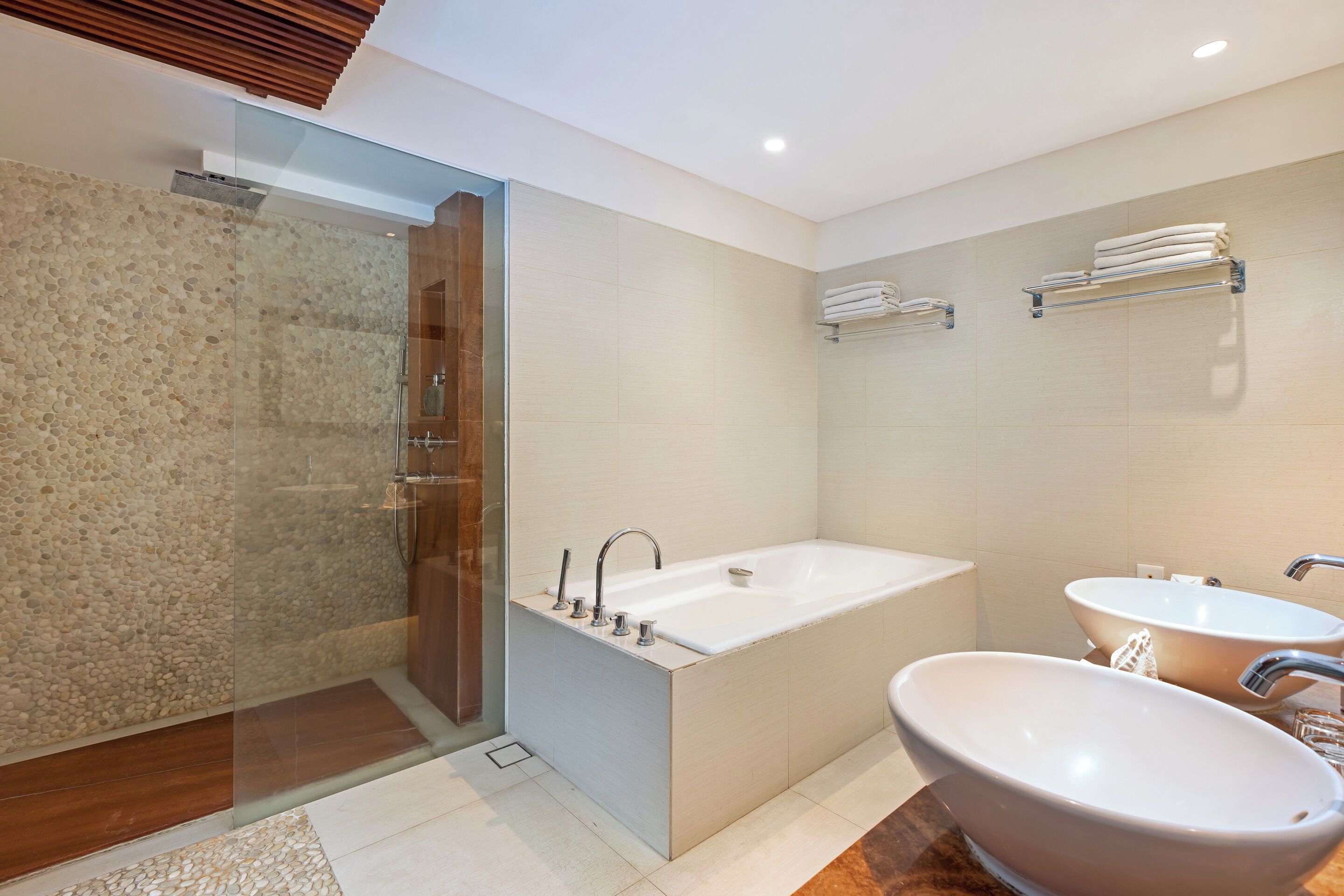 A modern bathroom with a glass-enclosed shower, a freestanding bathtub, and two sinks.