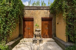 A traditional building with two wooden doors, a stone pathway, and a potted plant in the center. - Ubud Green Resort Villas Powered by Archipelago (Ubud)