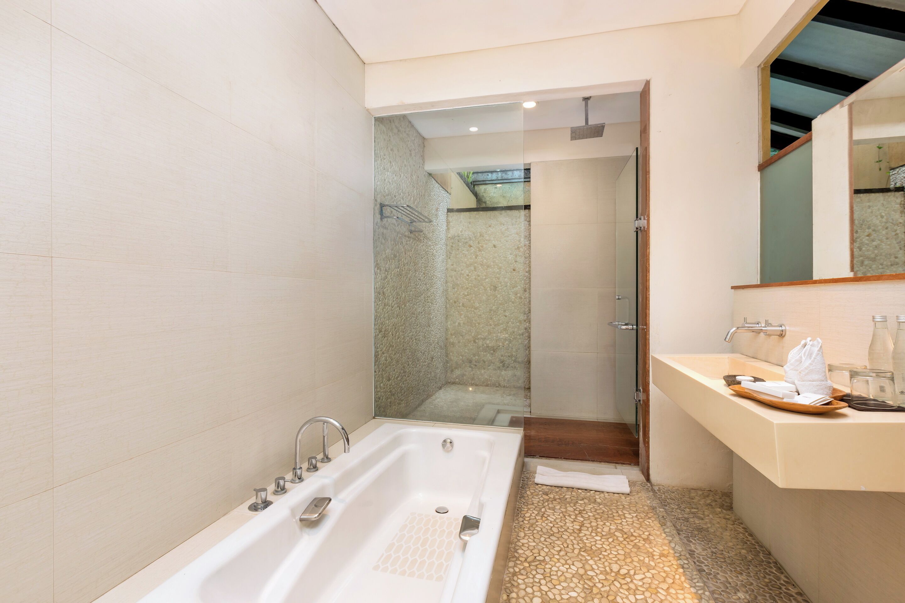 A modern bathroom with a large bathtub, a glass-enclosed shower, and a vanity with a mirror.