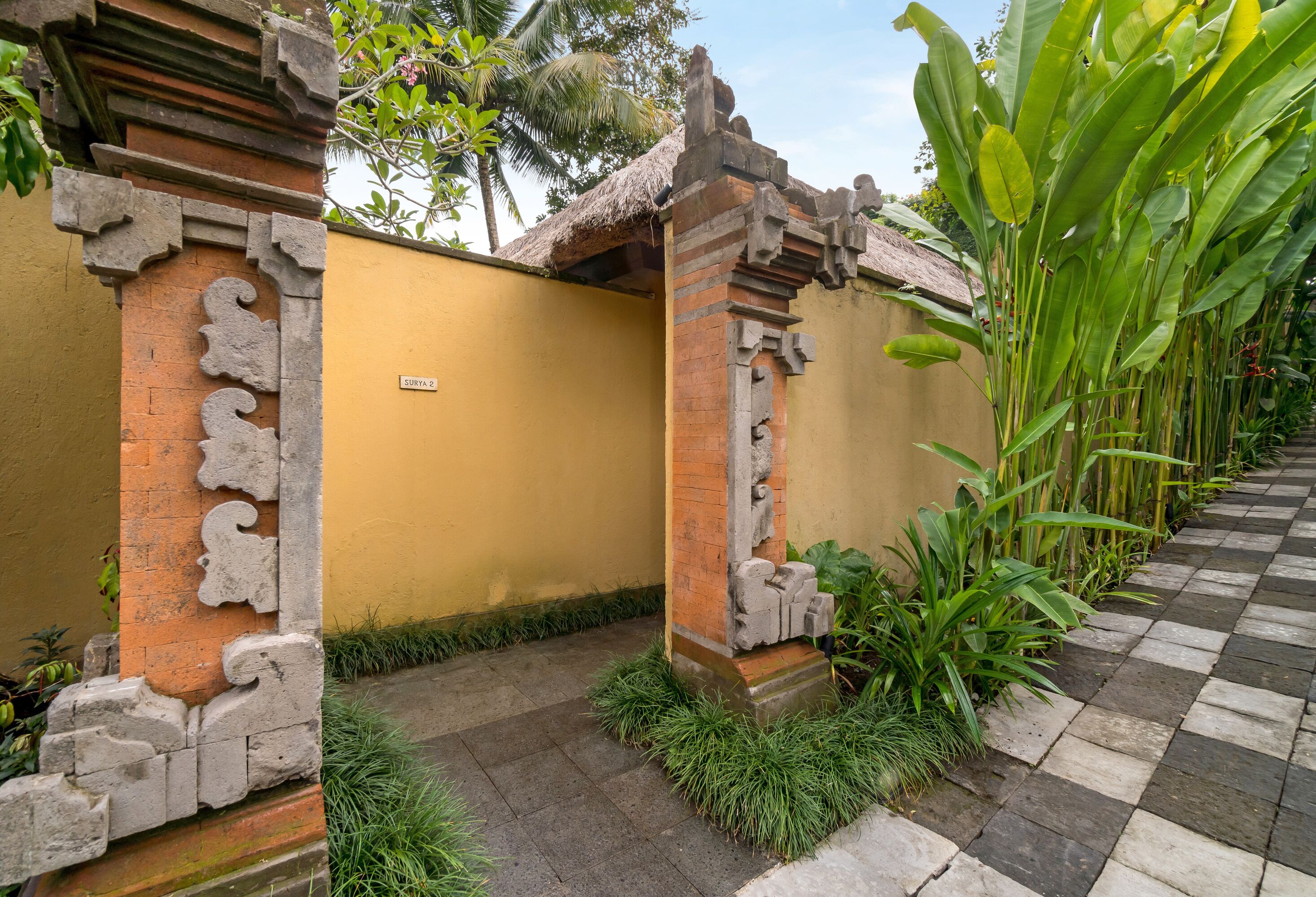 A traditional building with a yellow wall and a checkered pathway.