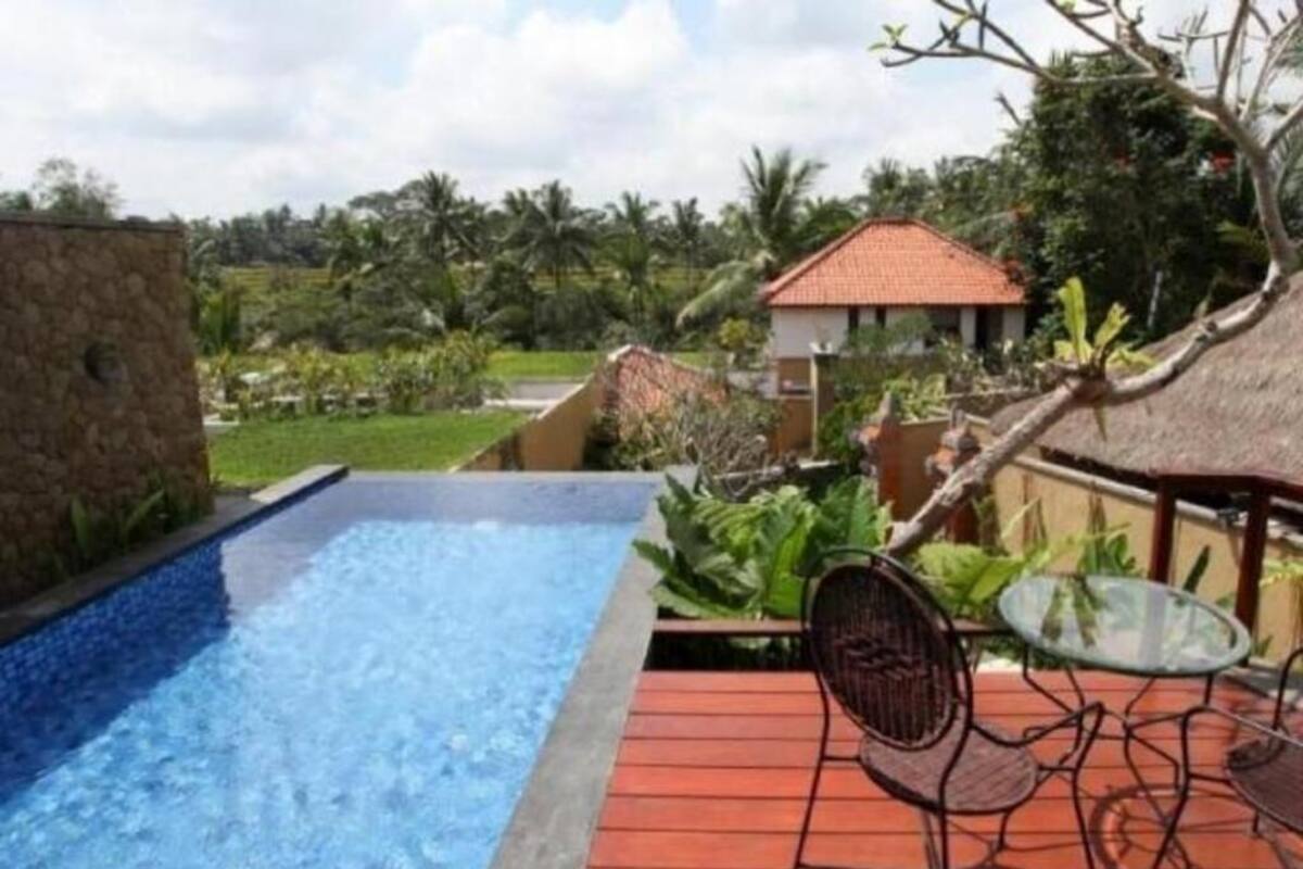 A swimming pool with a wooden deck, a glass table, and chairs.