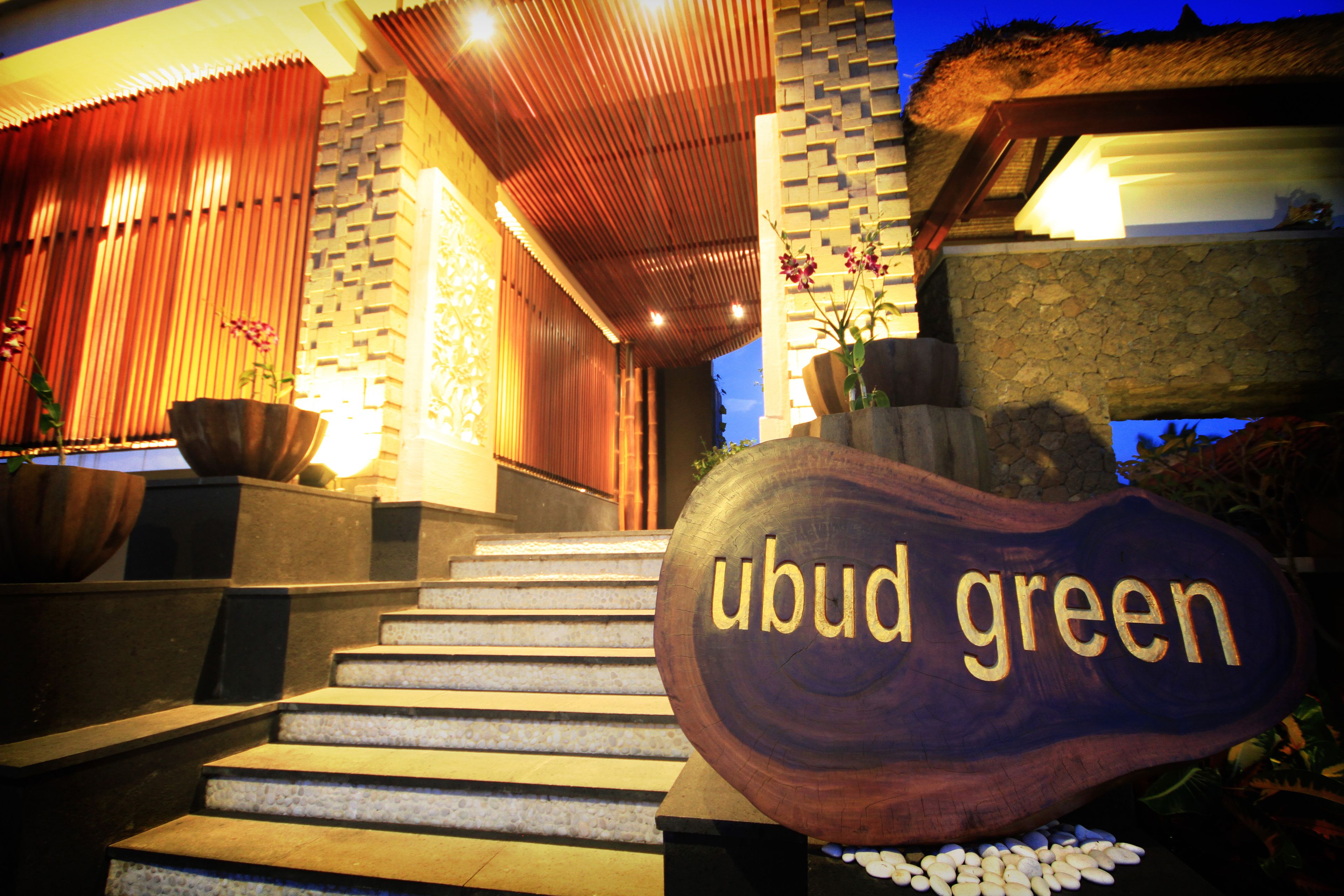 A wooden sign with "ubud green" engraved, a stone staircase, and a thatched roof structure.