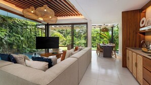 Uma sala de estar moderna com um sofá grande, uma TV e um espaço de jantar com mesa e cadeiras.
