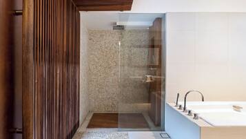 Un baño moderno con ducha envuelta en vidrio, una bañera grande y un diseño de paneles de madera.