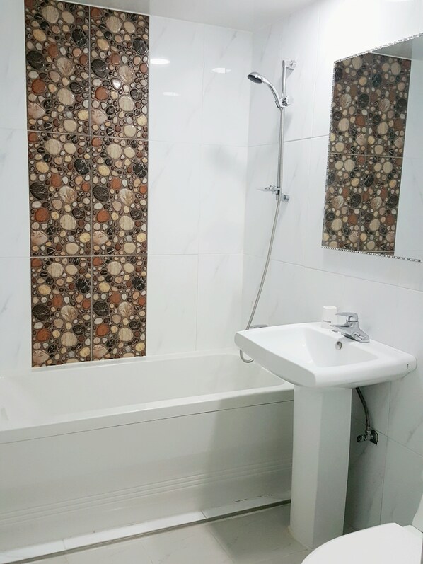A bathroom with a bathtub, a sink, and a mirror.