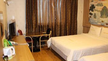 Habitación de hotel con cama, escritorio, silla, teléfono y televisor.
