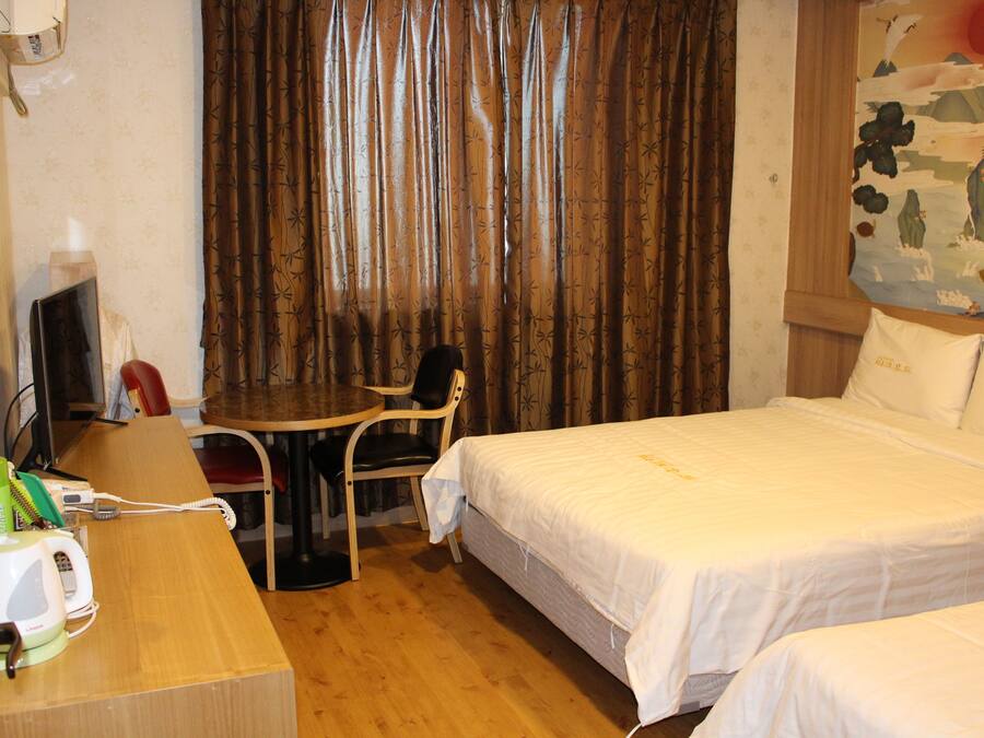Habitación de hotel con cama, escritorio, silla, teléfono y televisor.