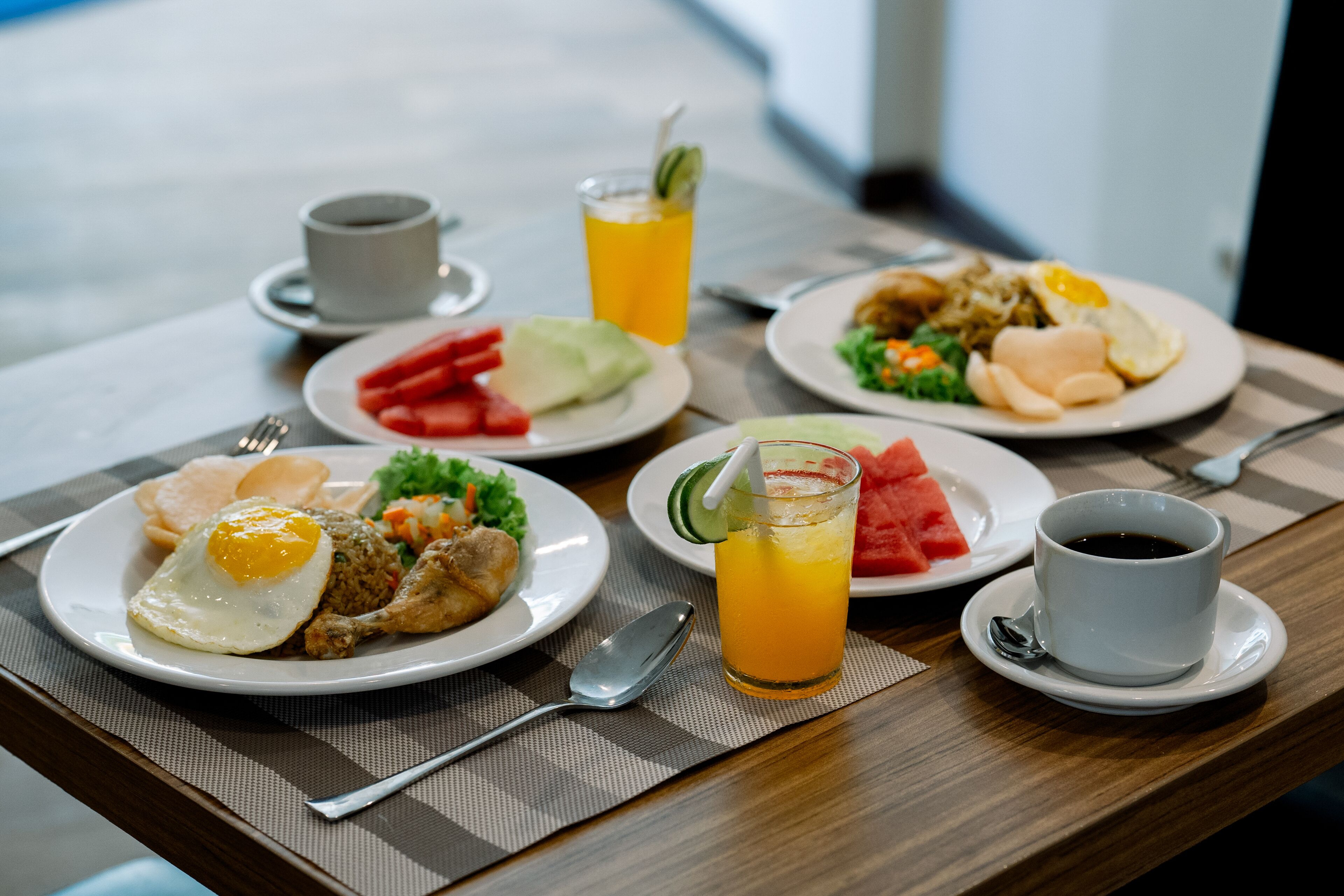 A breakfast table with plates of food, a glass of orange juice, and a cup of coffee.