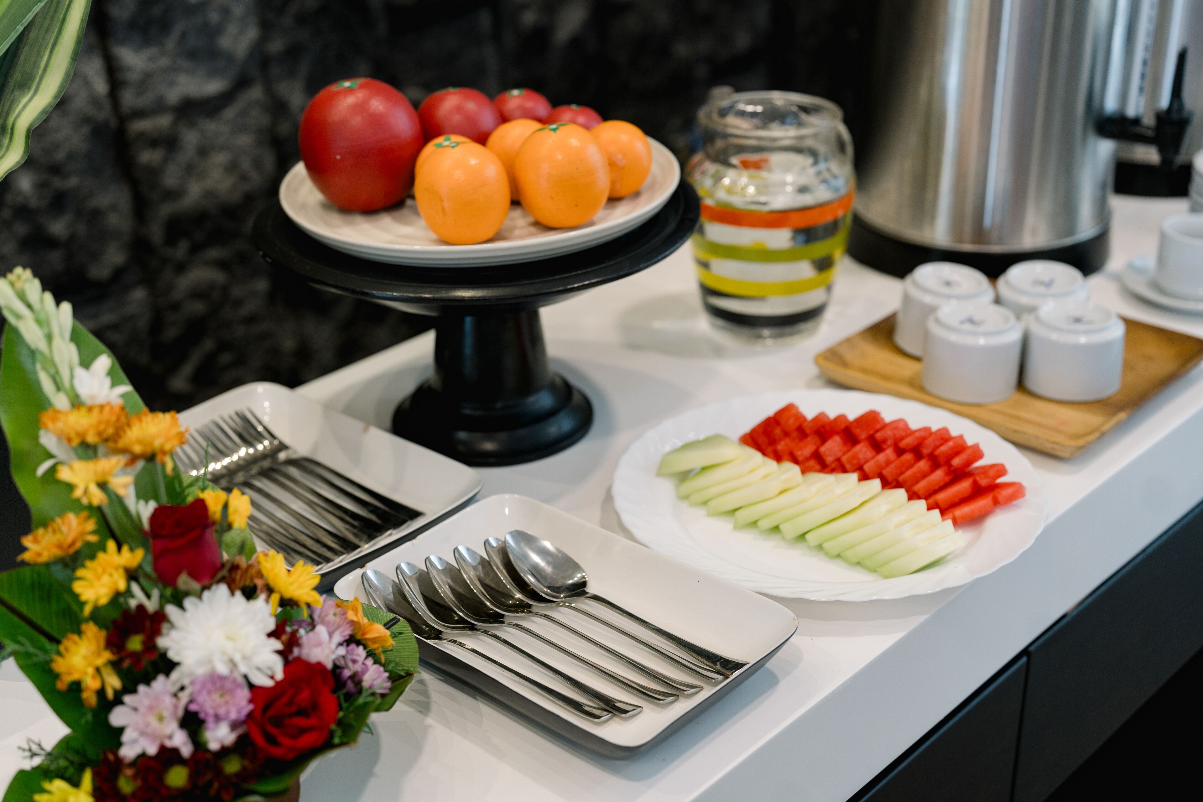 A buffet table with fruits, vegetables, and utensils.