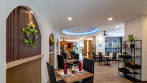 A restaurant with wooden paneling, a circular ceiling light, and a dining area with tables and chairs. - Everyday Hotel Kuta Central (Kuta)