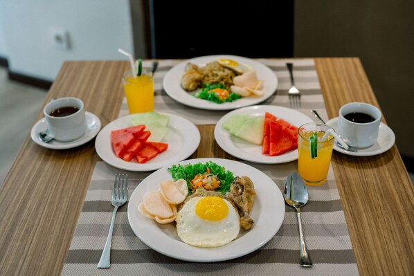 A dining table with plates of food, including an egg, meat, and vegetables, and two glasses of orange juice.