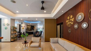 A modern living room with a sofa, a coffee table with fruit, and a dining area in the background. - Everyday Hotel Kuta Central (Kuta)