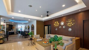 A modern hotel lobby with a central seating area, a dining space, and a reception desk. - Everyday Hotel Kuta Central (Kuta)
