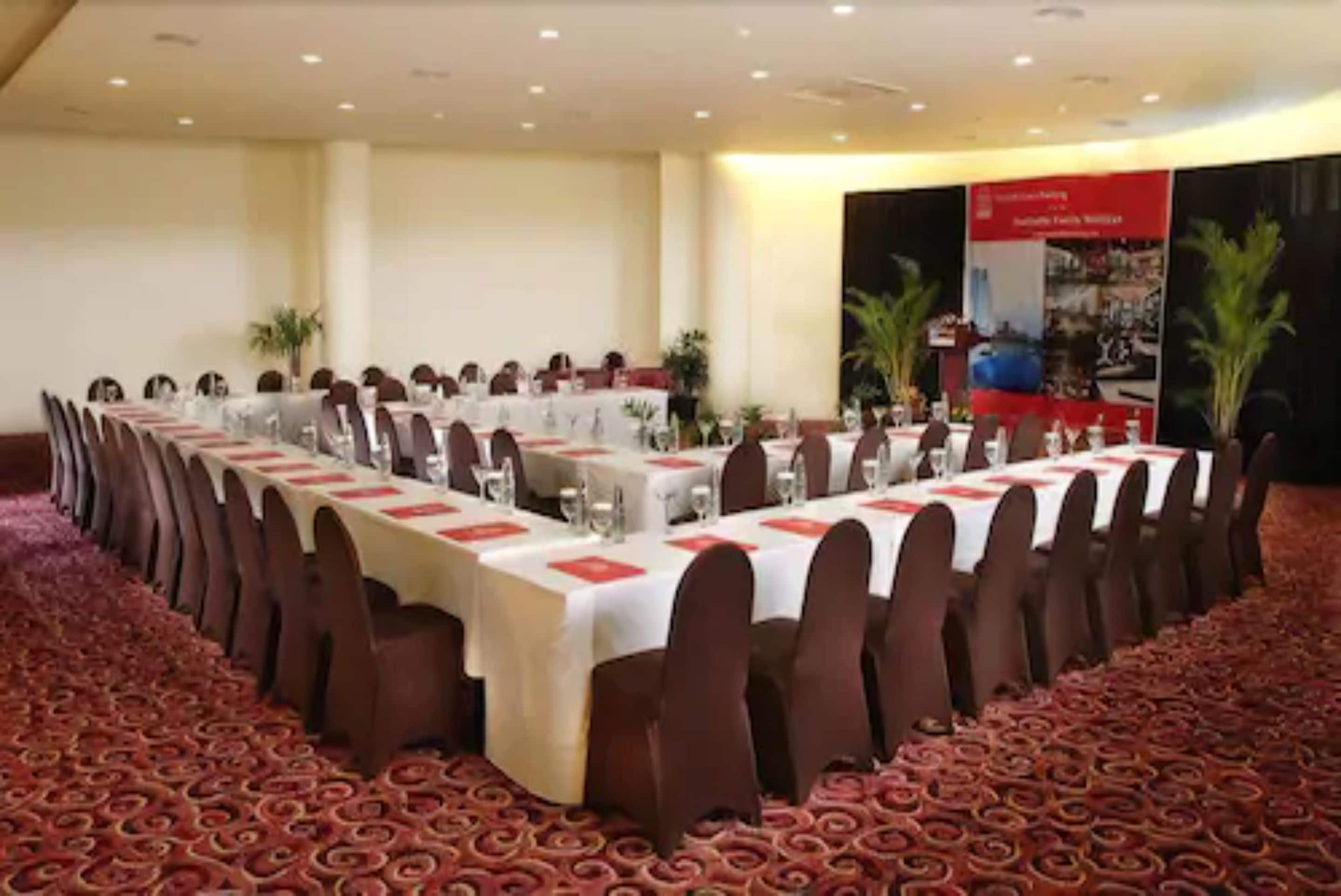A conference room with a long table set for a meeting, surrounded by chairs.