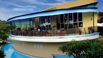 A building with a curved roof, a pool, and outdoor seating.