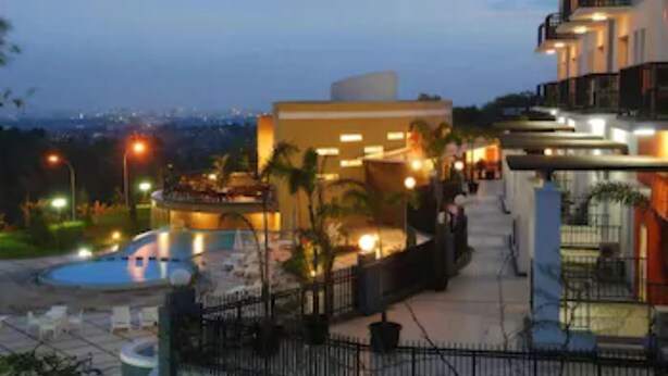 A hotel with a swimming pool, outdoor seating, and a view of the city at dusk. - Marbella Suites Bandung (Bandung)